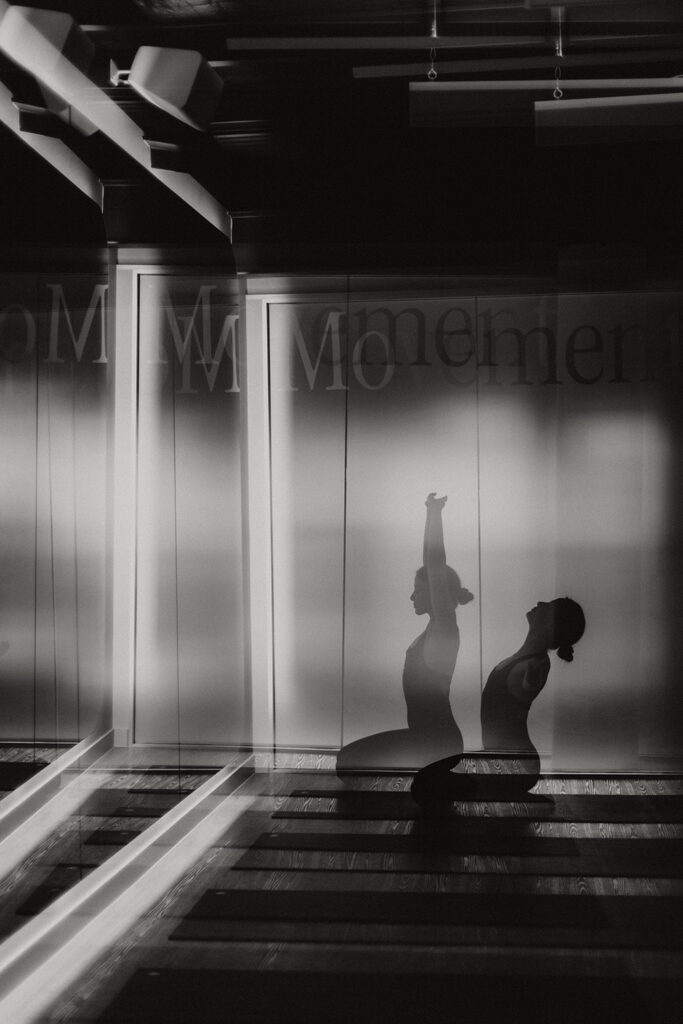 Double exposure of a woman in seated yoga poses with arms raised and arched back, captured in a movement studio by a Sunshine Coast brand photographer.