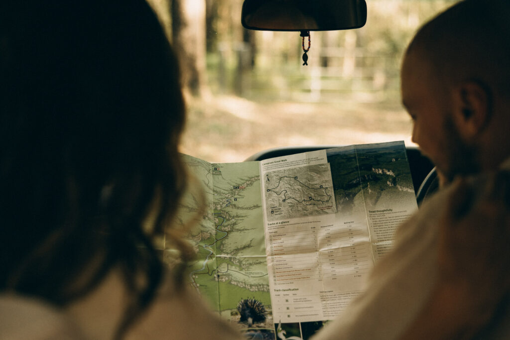 Cinematic Sunshine Coast couples session in the hinterland forest, capturing a nostalgic van-life moment of a couple reading a map and planning their adventure together.
