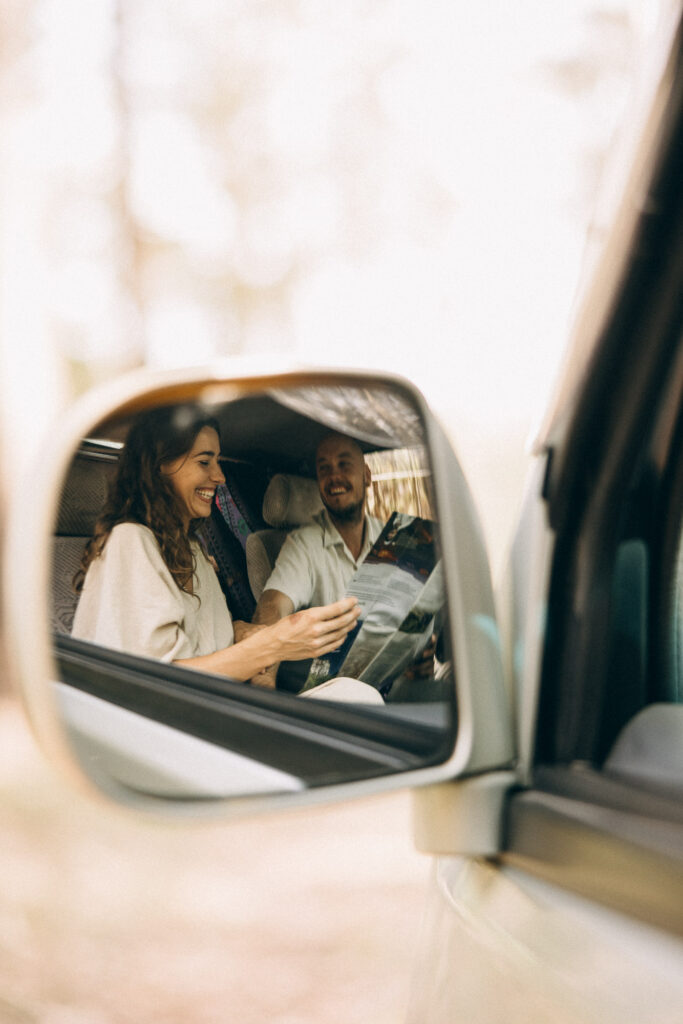 Couple laughing in a campervan, reflected in a side mirror, during a cinematic Sunshine Coast couples photography session. A playful, candid moment documenting adventure, connection, and van-life storytelling in the Sunshine Coast hinterland.