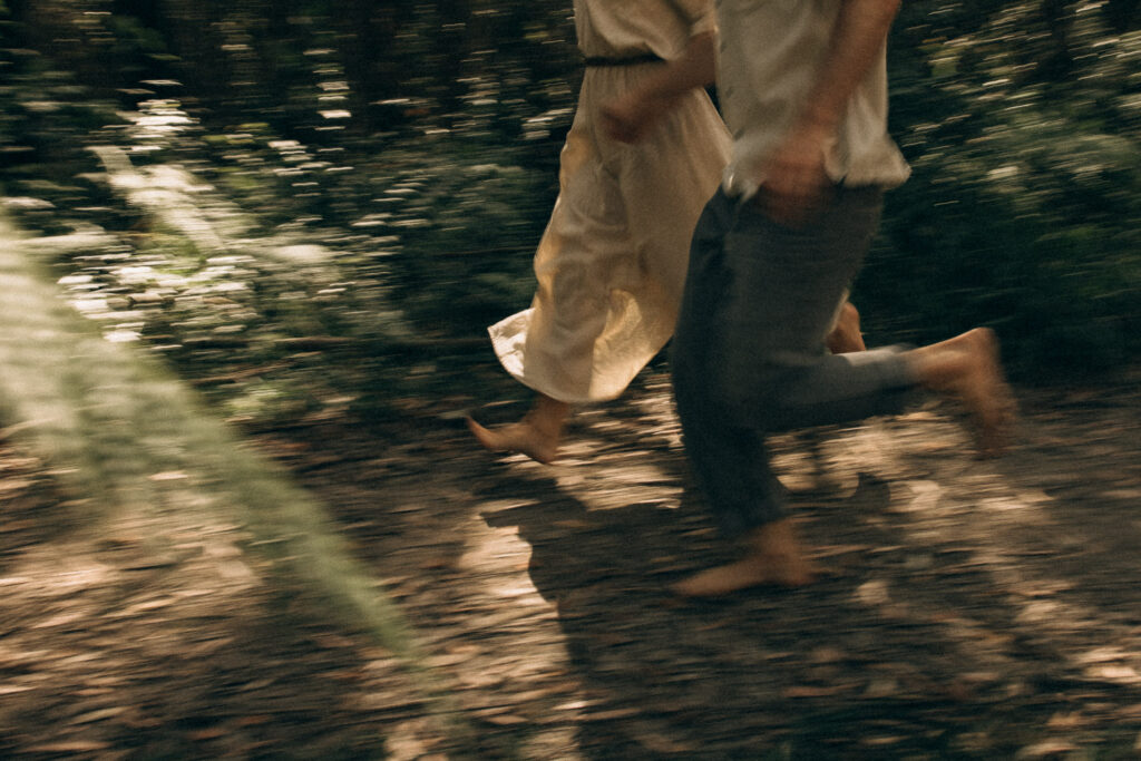Adventure couples photography in the Sunshine Coast Hinterland, featuring a cinematic motion-blur moment of lovers running barefoot through the forests of Mapleton and Maleny during a storytelling session.
