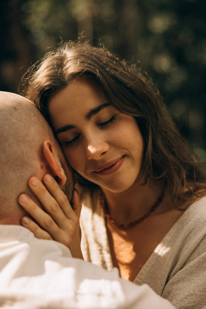 Intimate Sunshine Coast couples photography in the hinterland forest, capturing a soft cinematic moment of a woman holding her partner close during a nostalgic storytelling session.