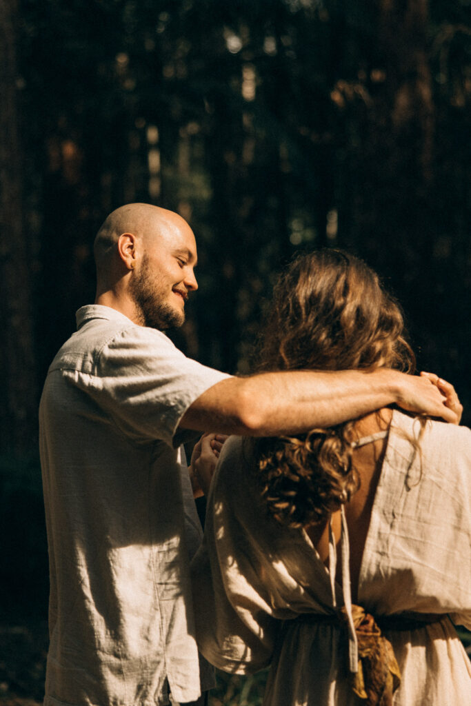 Cinematic hinterland couples session on the Sunshine Coast, capturing a warm, documentary-style moment of a couple walking together through the forest at golden hour.