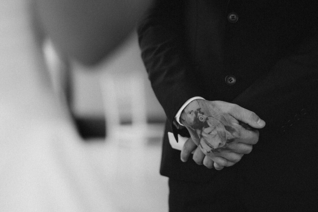 Bride and groom walking hand in hand through a dim hallway toward a lit window after their Brisbane Registry Office ceremony