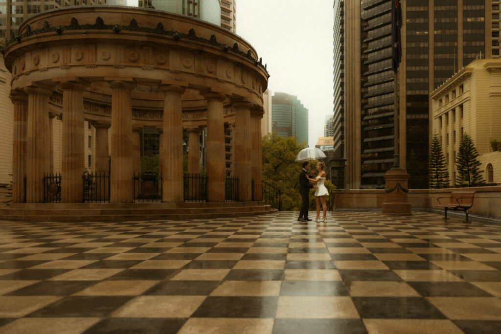 Couple dancing in the rain under umbrellas, who eloped near Anzac Square
