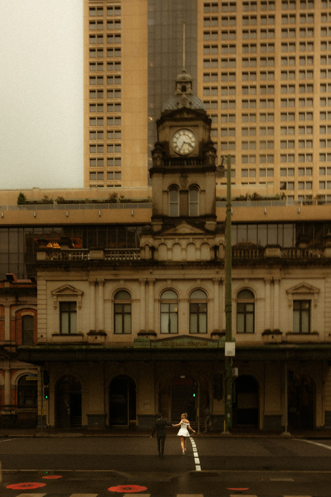 white wide shot of bride and groom running across the street in front of Central Station