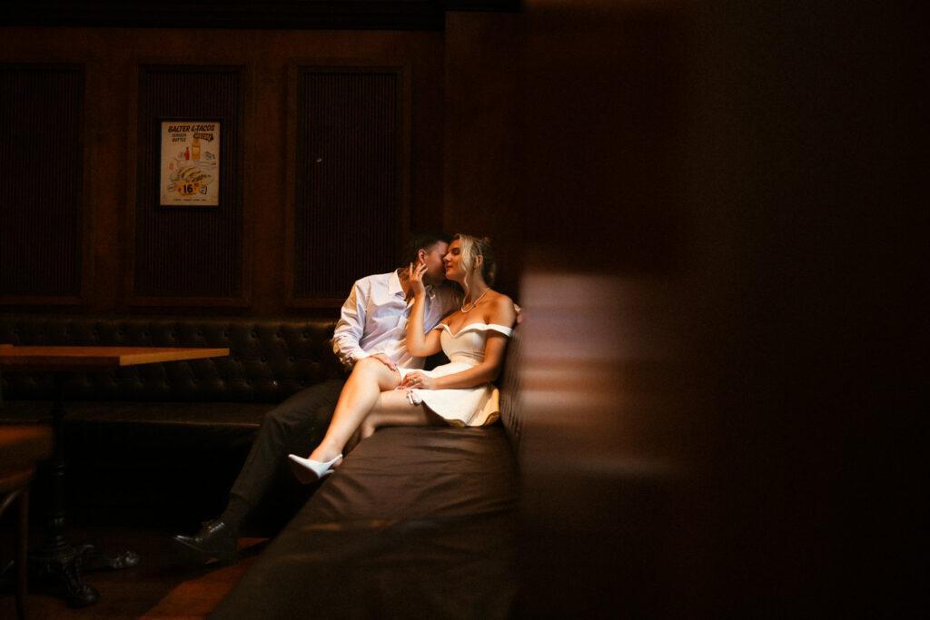 Inside a brisbane city pub, a bride and groom snuggle into a moody booth