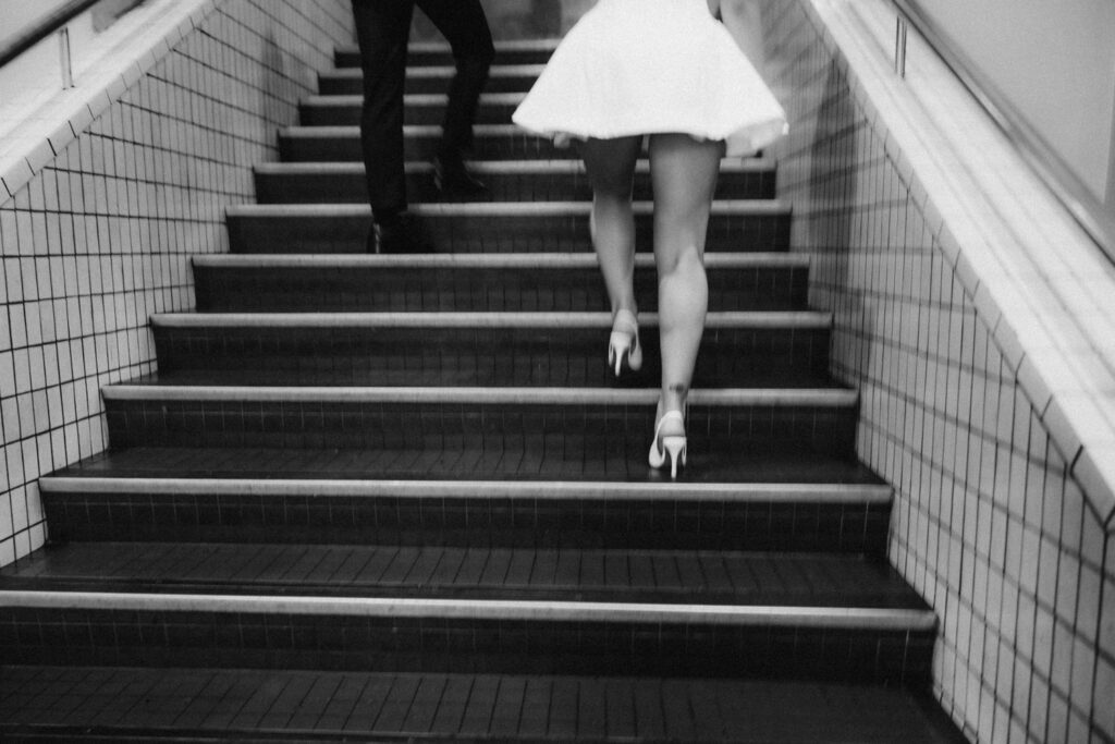 Black and white shot of the bride's legs and heels running down station stairs