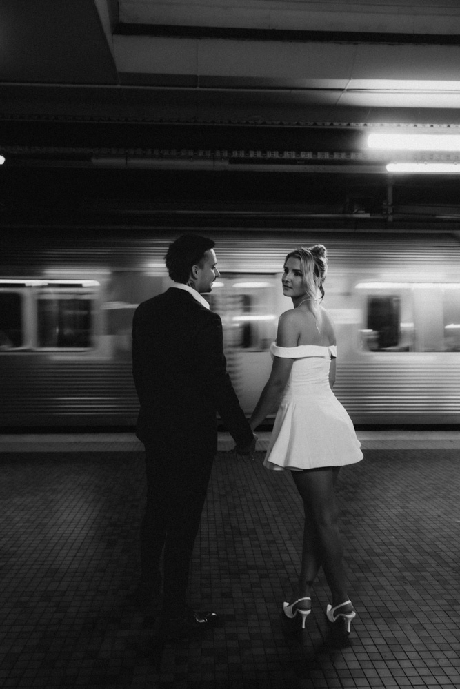 Couple on platform at central railway station brisbane holding hands after getting married - black and white