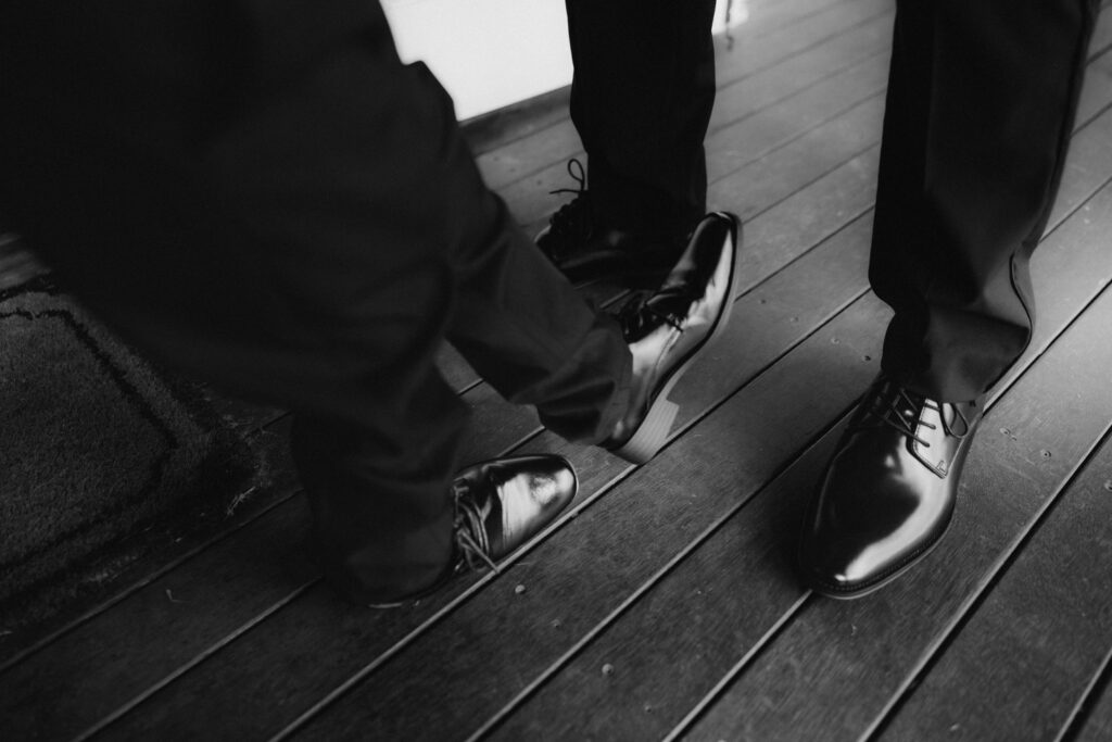 Black and white image of groom feet with shoes on and his sons