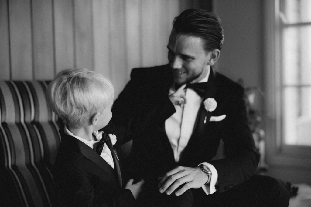 Black and white image of groom and young son admiring each other