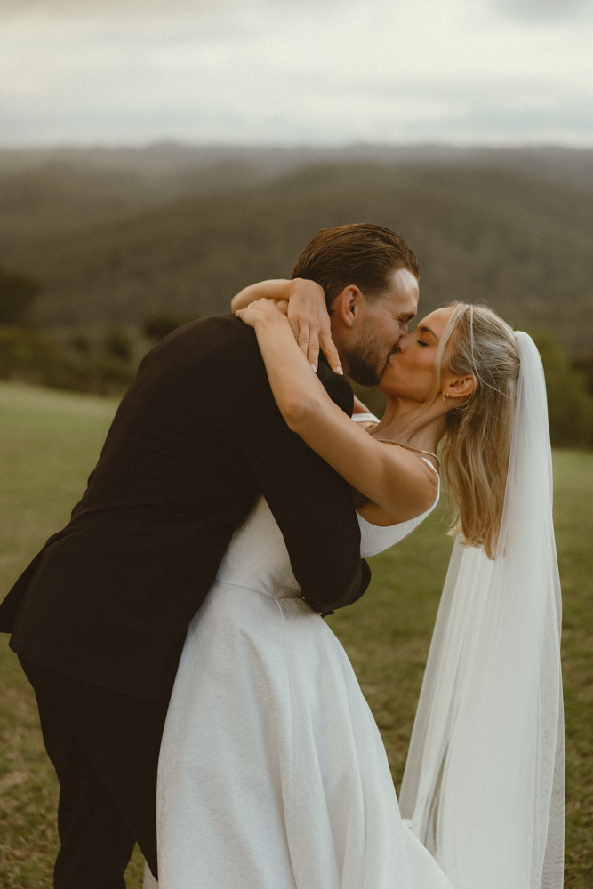 Groom dipping bride after their wedding ceremony on the grass Sunshine Coast Hinterland
