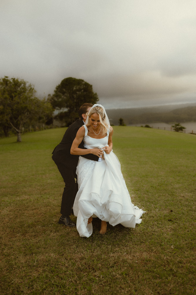 groom chasing his wife on the grass at their elopement 