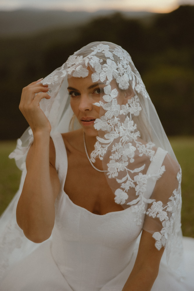 editorial portrait of bride holding a veil - close oup of face and hands looking driectly into the camera