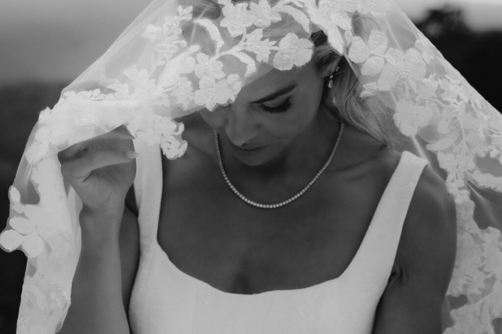 black and white close up of bride looking down with the focus on the detailed lace of her veil