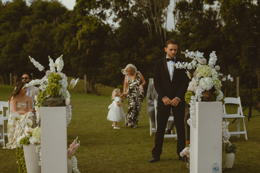 Groom waiting for bride to walk down the isle, grandmother and grooms daighter behind