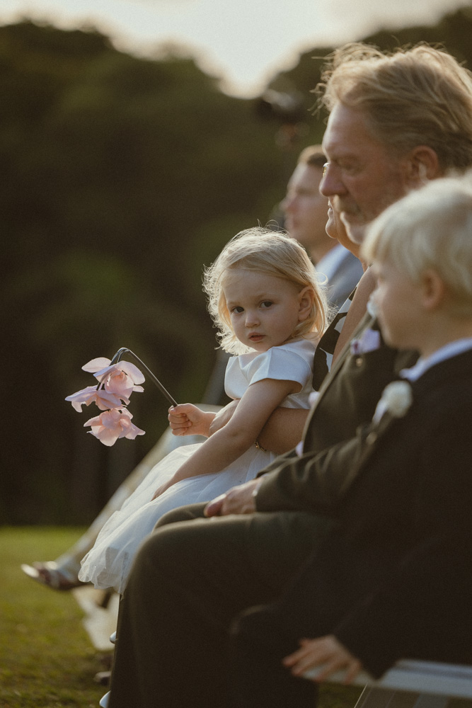The couples daughter holding floral decoration sitting on grandmothers lap during the ceremony