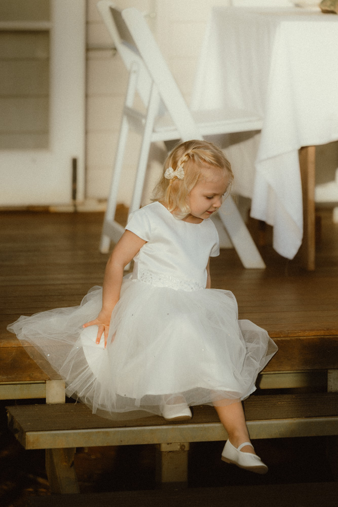 Couples daughter in her flower girl dress sitting on the steps at elopement venue - The Lake House Folk