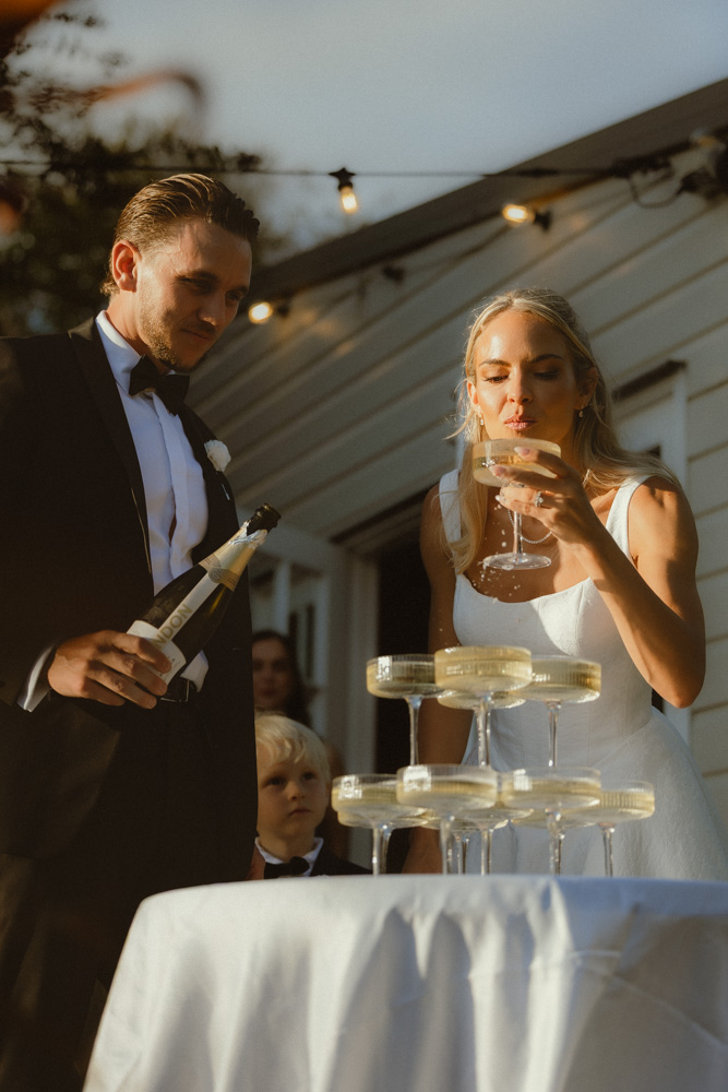 Couple drinking champagne from tower at golden hour after their elopement