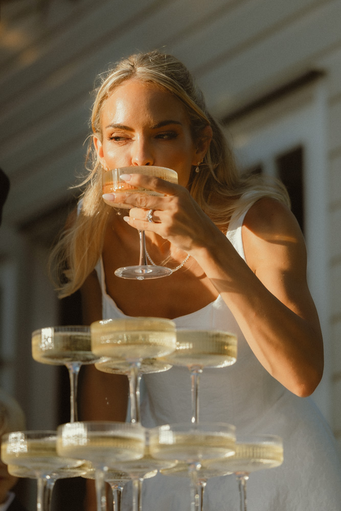 bride drinking champagne from tower at golden hour after their elopement